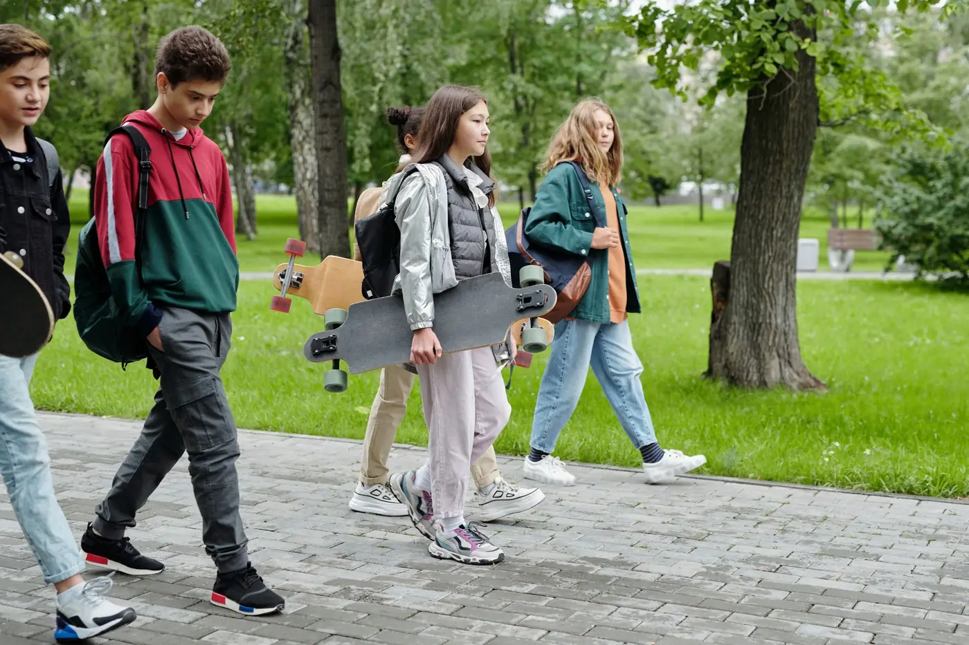 A group of teenagers walking through a park together after school