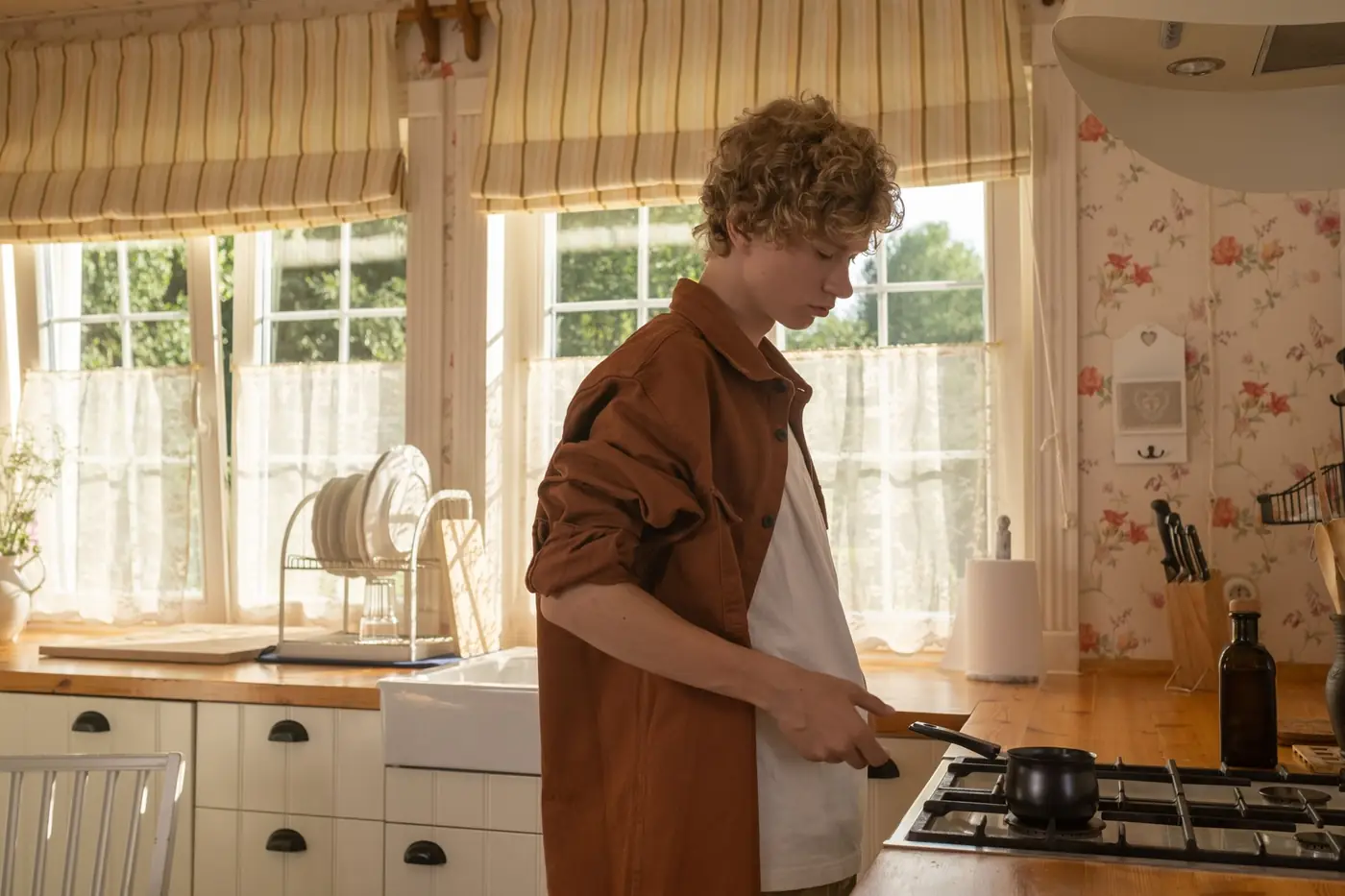 A teenager cooking in a sunny, homely kitchen