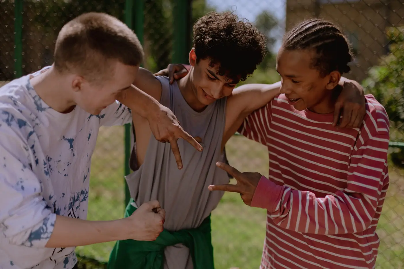 Three teenage friends laughing and joking together outdoors