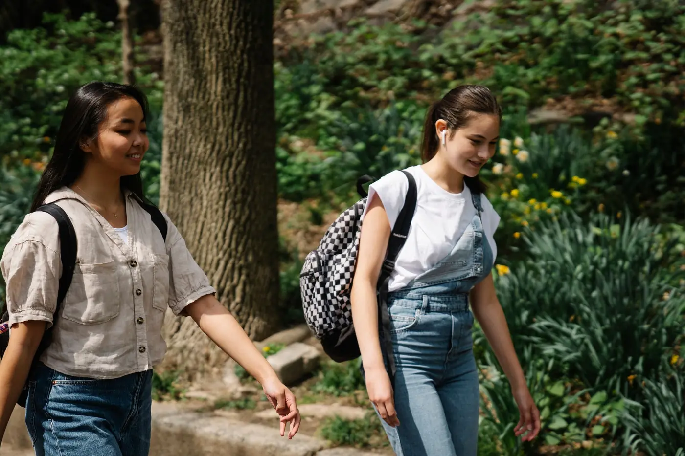 Two teenage girls walking together outdoors with their backpacks